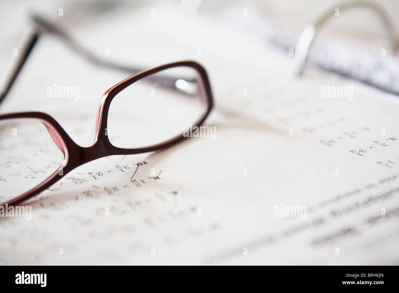 Nahaufnahme von Brillen auf Mathe-Hausaufgaben Stockfoto