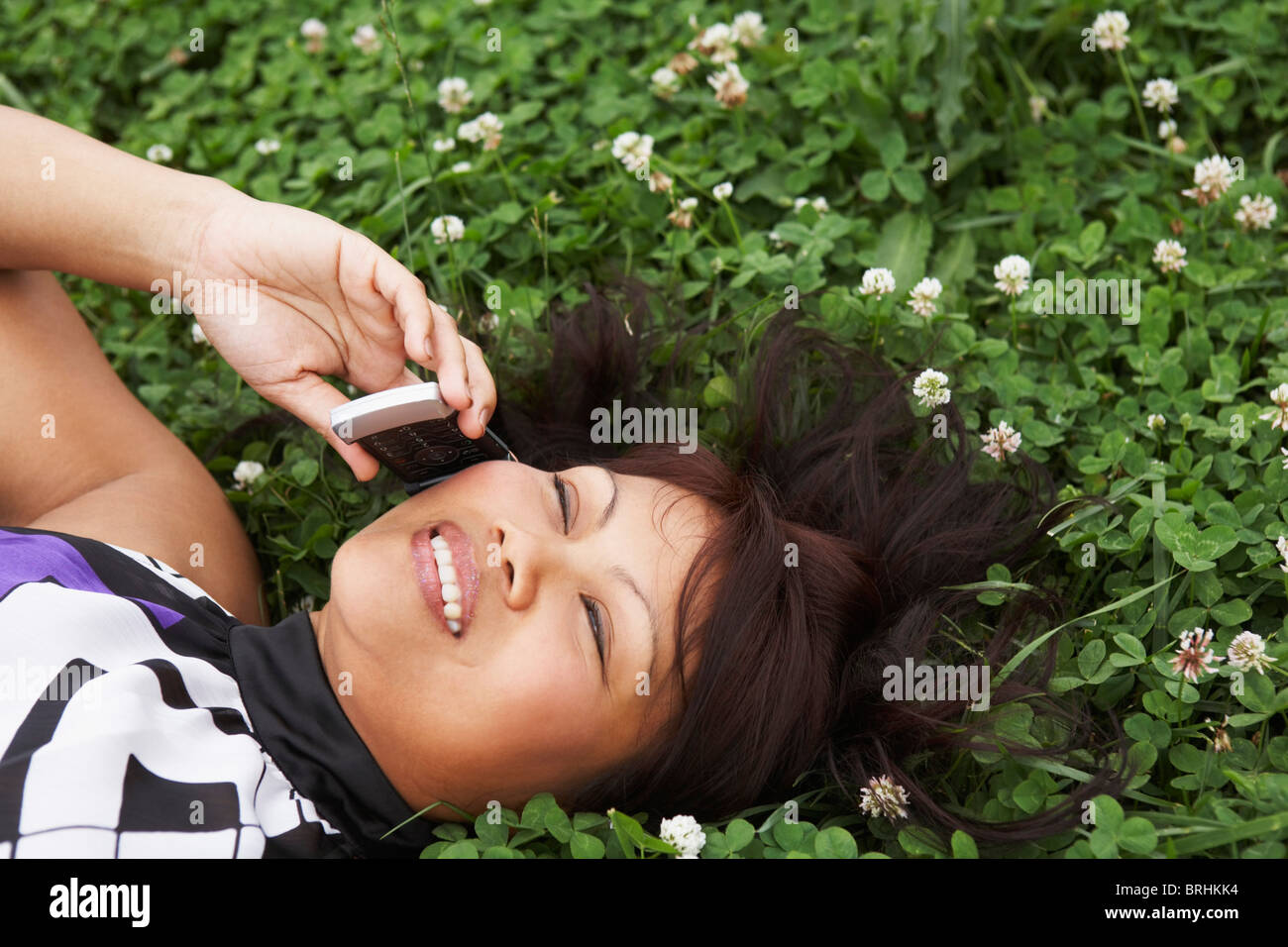 Frau liegend auf Klee Gebiet sprechen auf Handy Stockfoto