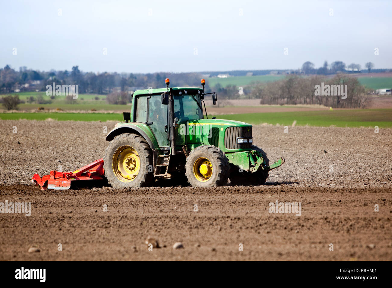 Traktor Eggen Feld nach dem Pflügen in Vorbereitung für die Aussaat von Frühling. Stockfoto