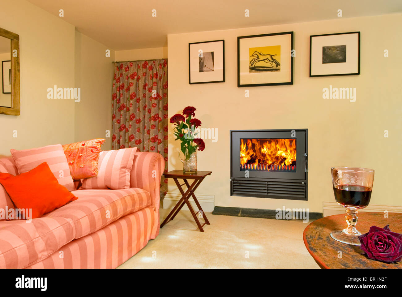 Ein Holzfeuer 18i einfügen Holzverbrennung Herd in ein Wohnzimmer mit Glas Wein im Vordergrund Stockfoto