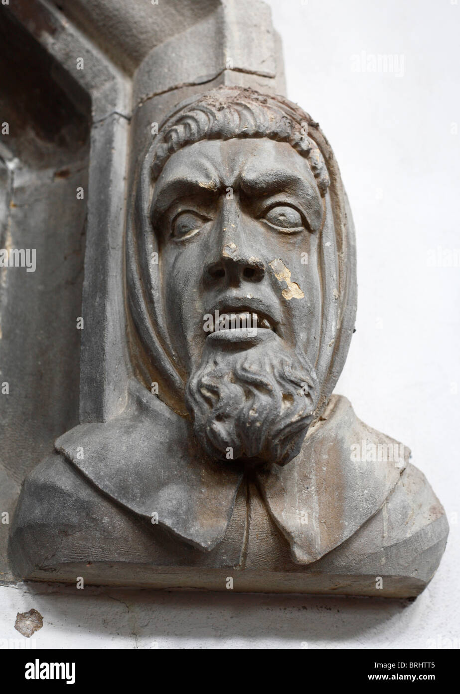 Ein geschnitzter Steinkopf im St.-Nikolaus-Kapelle, King's Lynn, Norfolk, England, mit einem gequälten Zeichenfolgenausdruck. Stockfoto