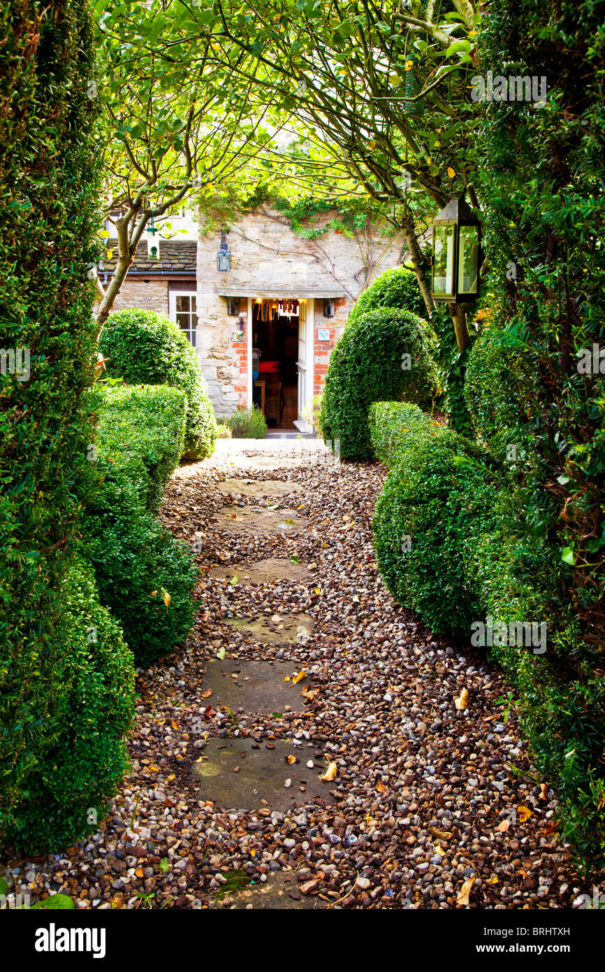 Gartenweg im Rückblick auf die Hintertür von einem englischen Landhaus aus Stein. Garten, entworfen von Rosemary Verey Stockfoto