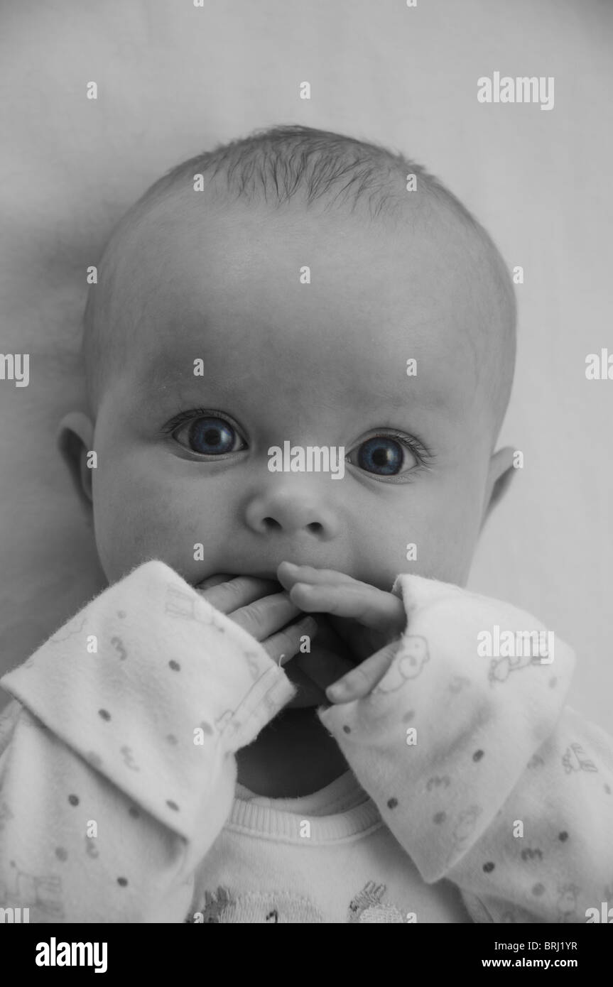 3 Monate altes Babymädchen saugen Finger schwarz & weiß mit blauen Augen Stockfoto