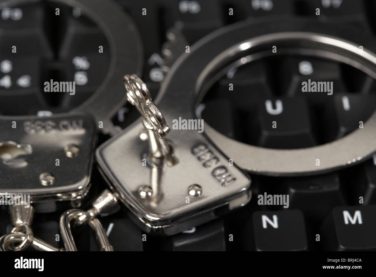 Schlüssel eingesteckt in Handschellen auf einer Computertastatur Stockfoto