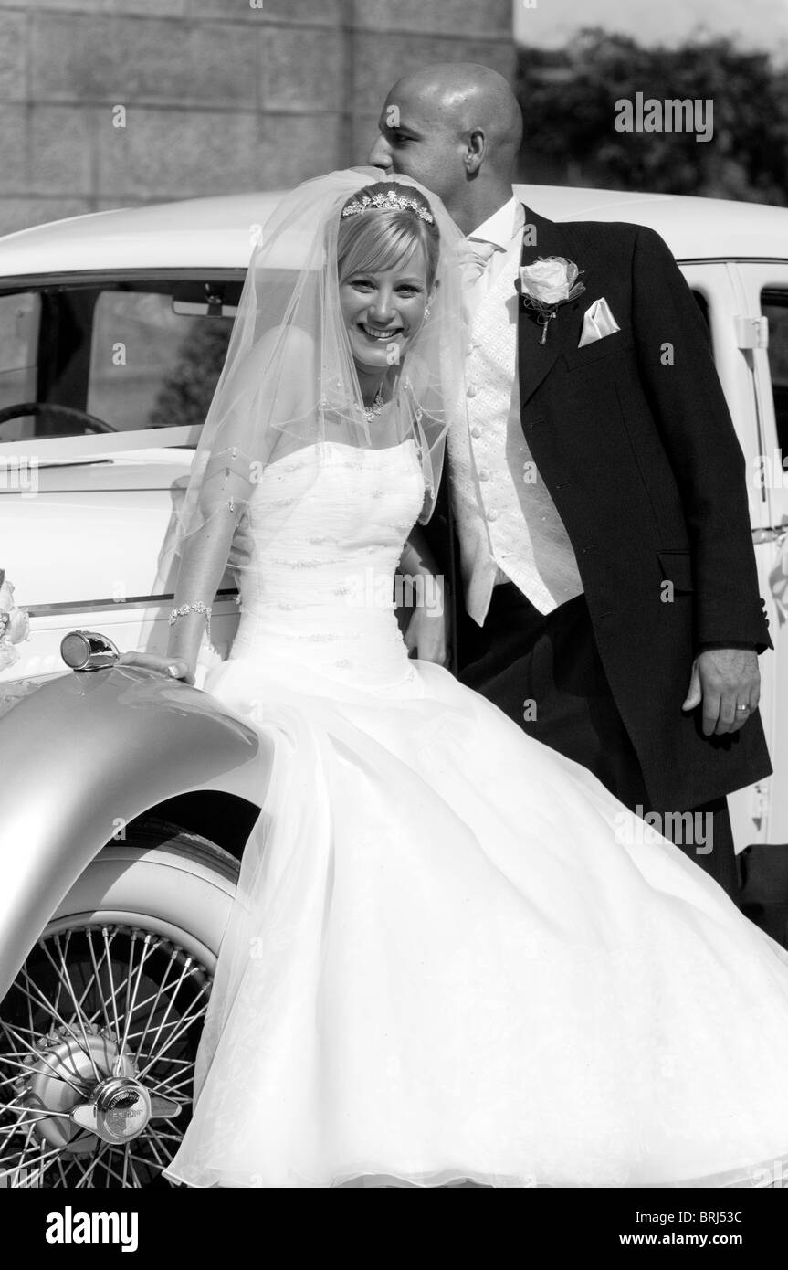 Eine atemberaubende aussehende Braut und Bräutigam neben Oldtimer Hochzeitsauto Stockfoto