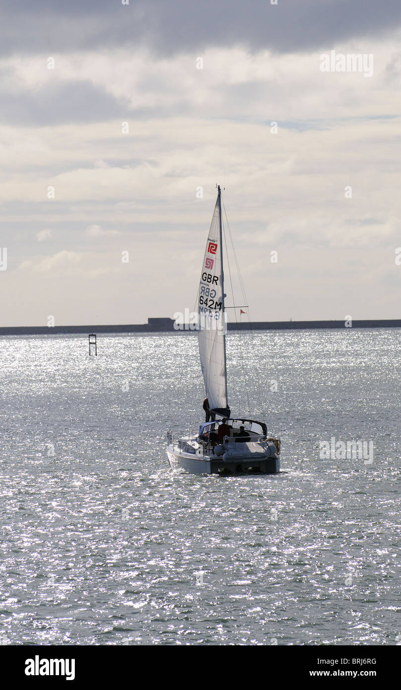 Plymouth Sound Devon England eine Yacht nähert sich die äußere Barriere gesehen unter Segel und gegen das Licht des frühen Morgens Stockfoto