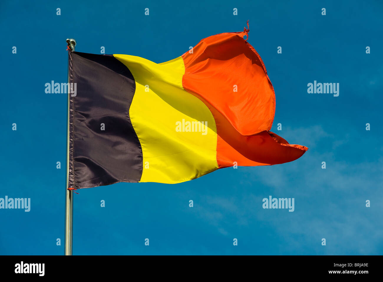 belgische Flagge auf einem Pfahl gegen blauen Himmel Stockfoto