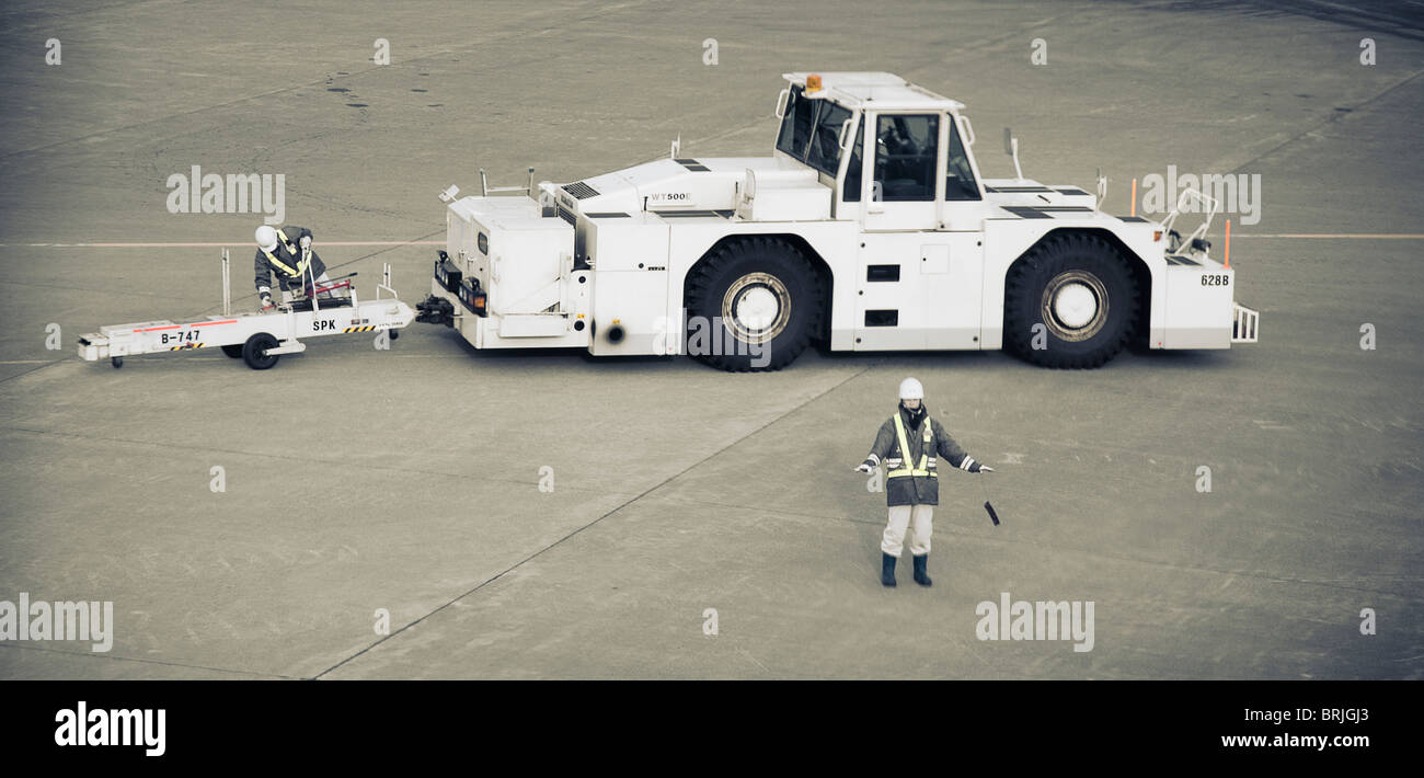 Flugzeug-Zugmaschine auf konkrete Rollfeld in Chitose Flughafen mit zwei Arbeiter arbeiten. Hokkaido, Japan. Stockfoto