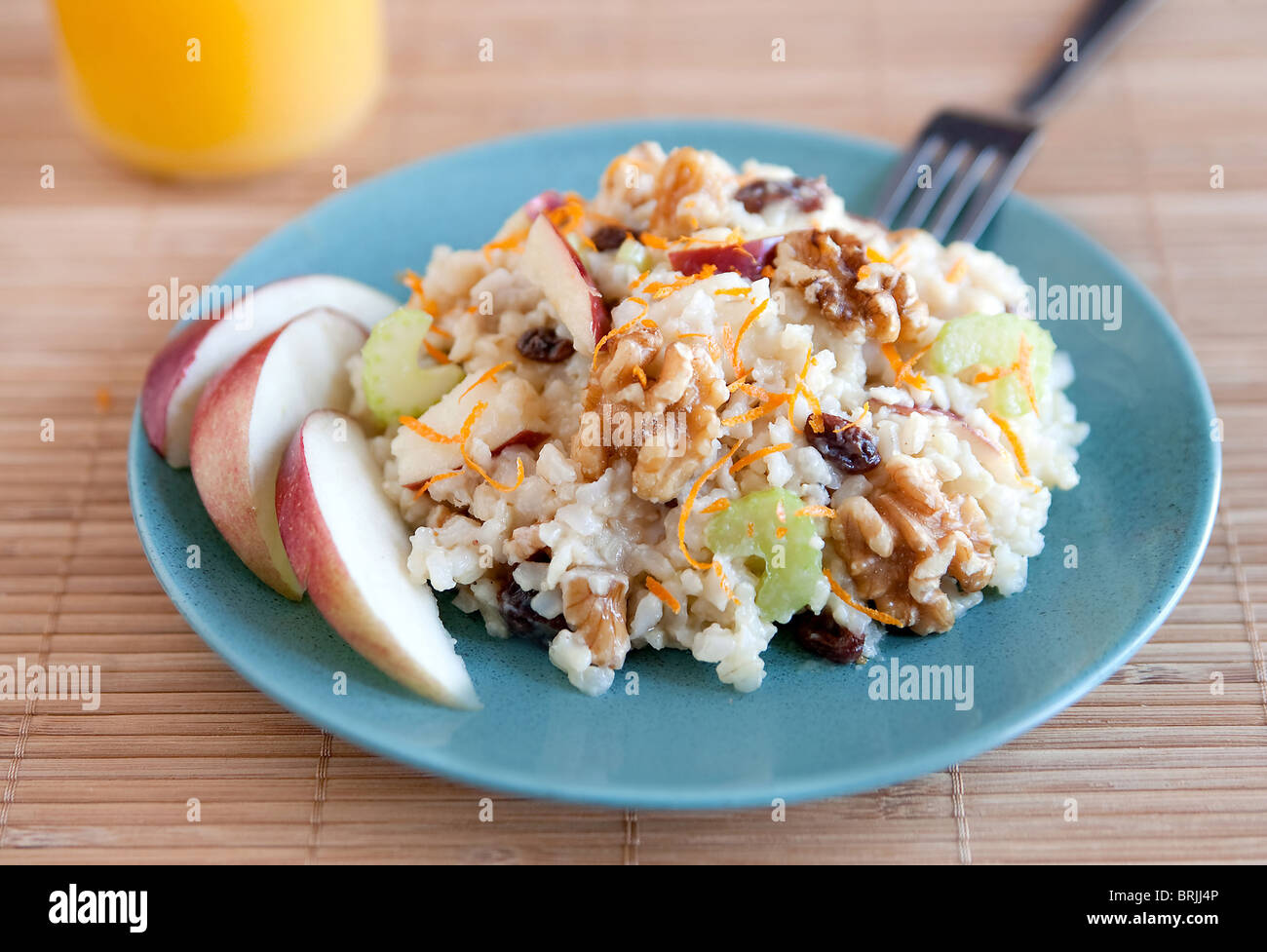 ein Teller mit Apfel Walnuss Salat ähnlich Waldorf-Salat auf einem blauen Teller mit Glas Orangensaft Stockfoto