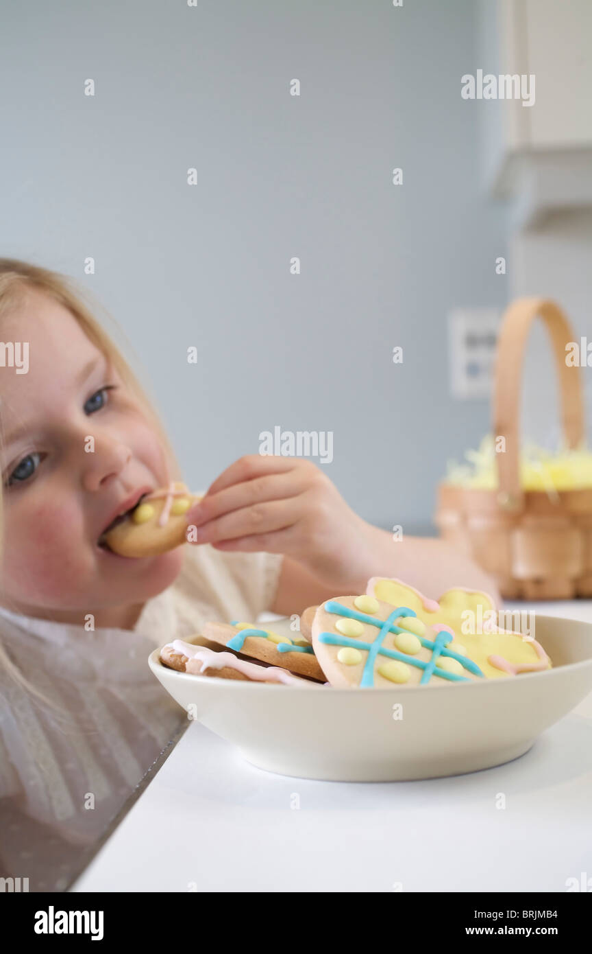 Kleine Mädchen essen Osterkekse Stockfoto