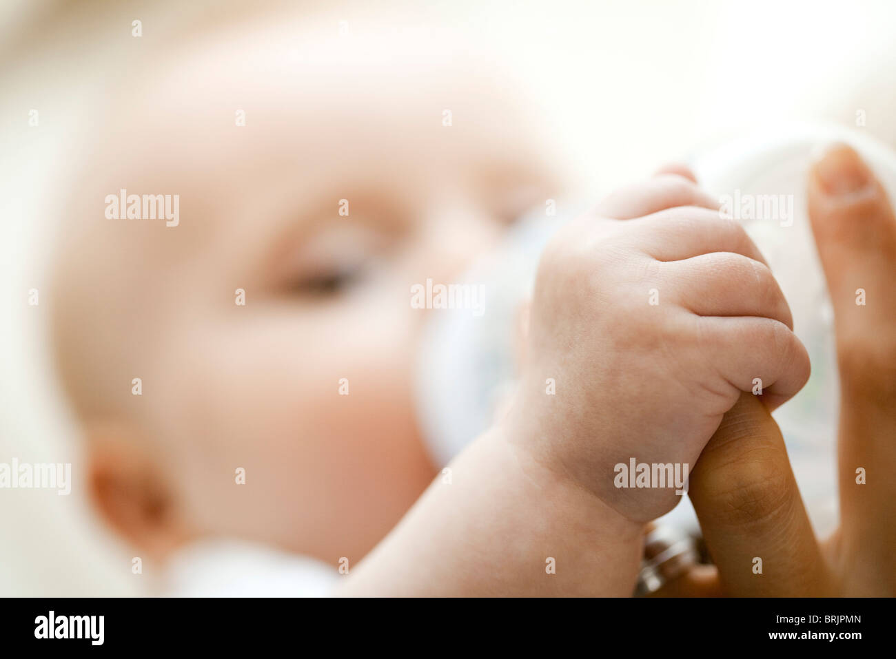 Baby trinken aus der Flasche und mit Mutters Finger, close-up Stockfoto