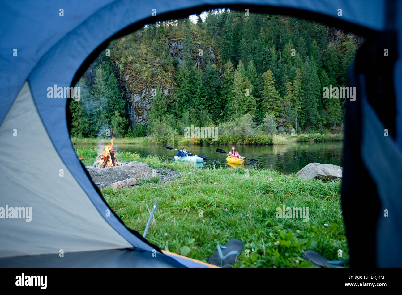 Junge Erwachsene paar camping mit einem Lager Feuer und Kajaks an einem schönen Sommerabend. Stockfoto