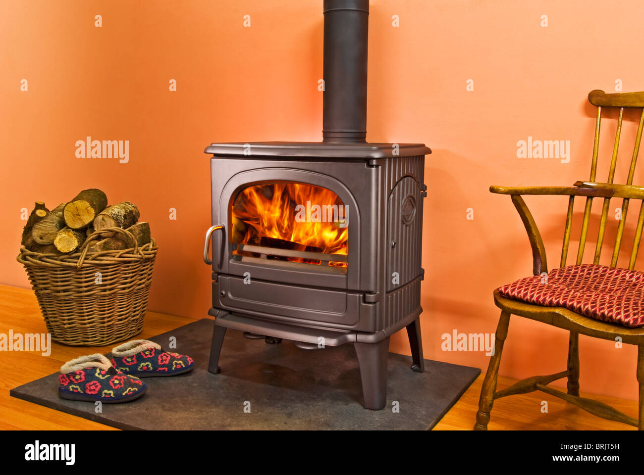 Dru 64 Holzofen Ofen mit Flammen und Log-Korb und Hausschuhe Stockfoto