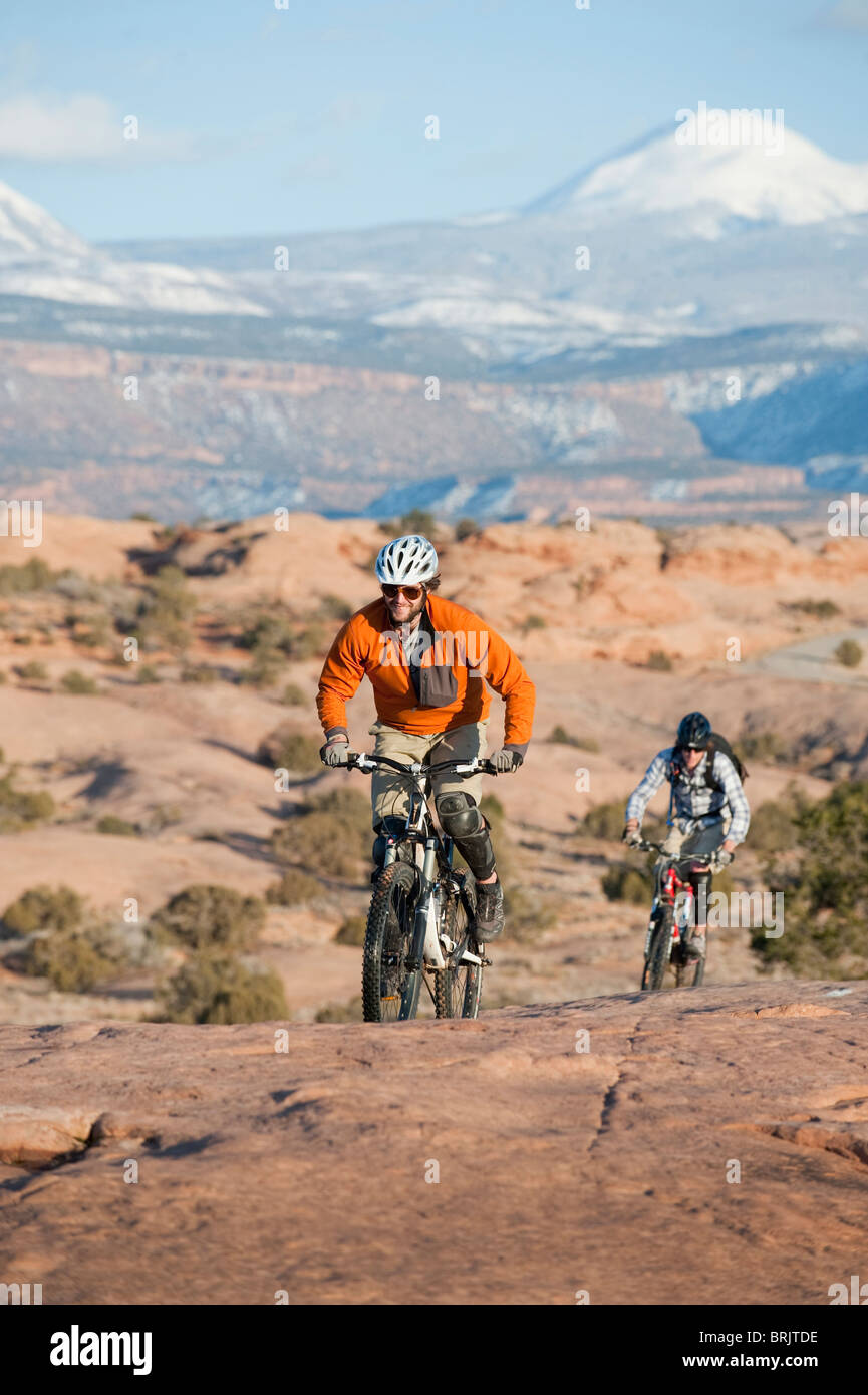 Zwei junge Männer fahren ihre Mountainbikes auf den Slickrock Trail, Moab, UT Stockfoto