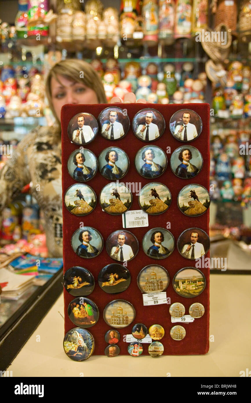 Shop Assistant hält eine Anzeige von Abzeichen von Peter dem großen und Putin St. Petersburg Russland Stockfoto