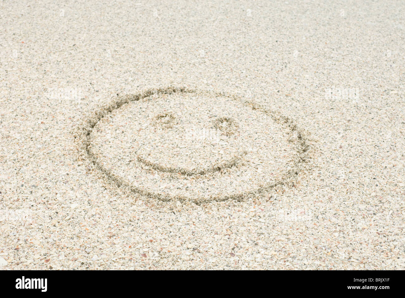Smiley-Gesicht gezeichnet im Sand am Strand Stockfoto