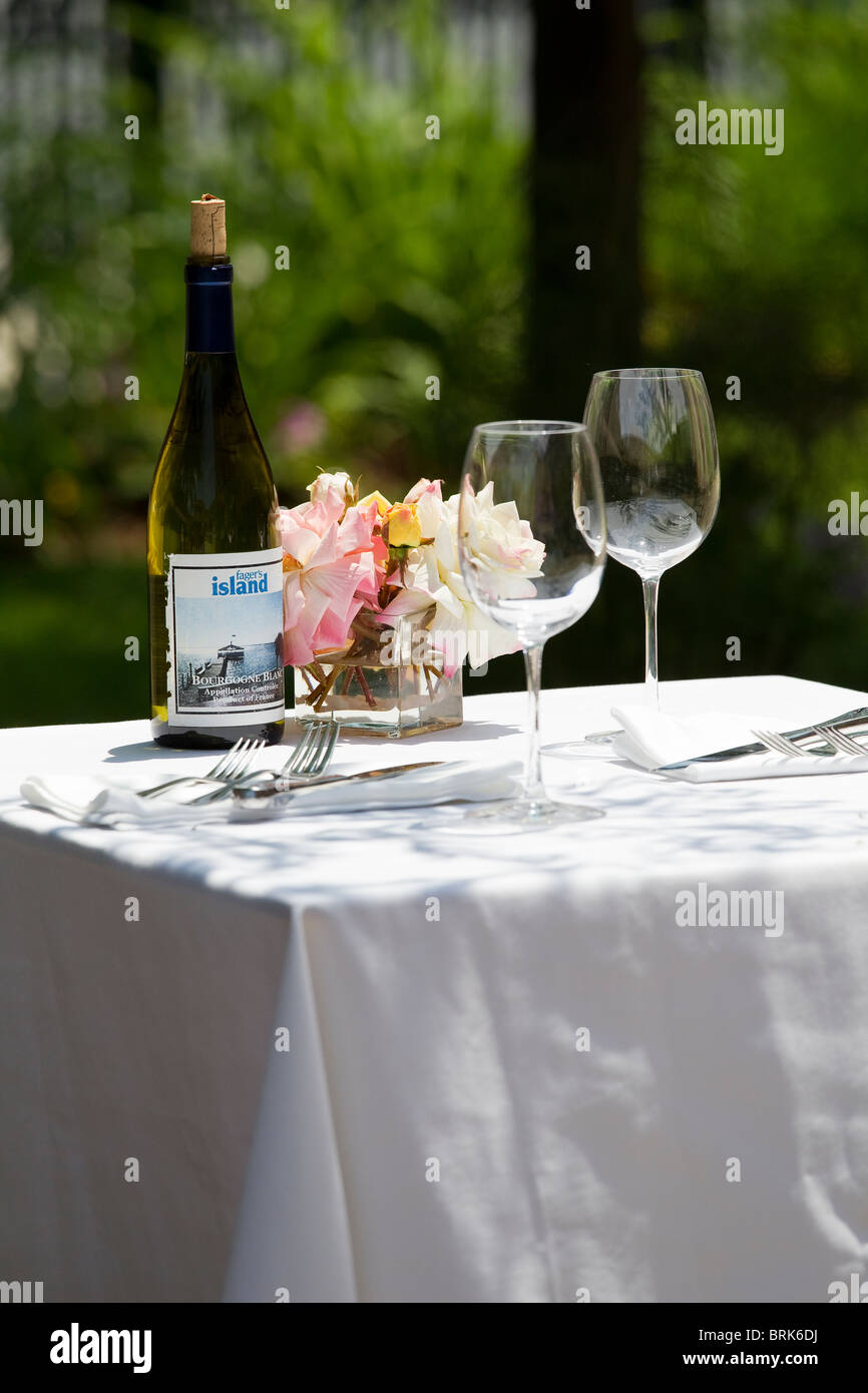 Weingläser und Weinflasche auf Tisch mit weißen Tischdecken außerhalb Stockfoto