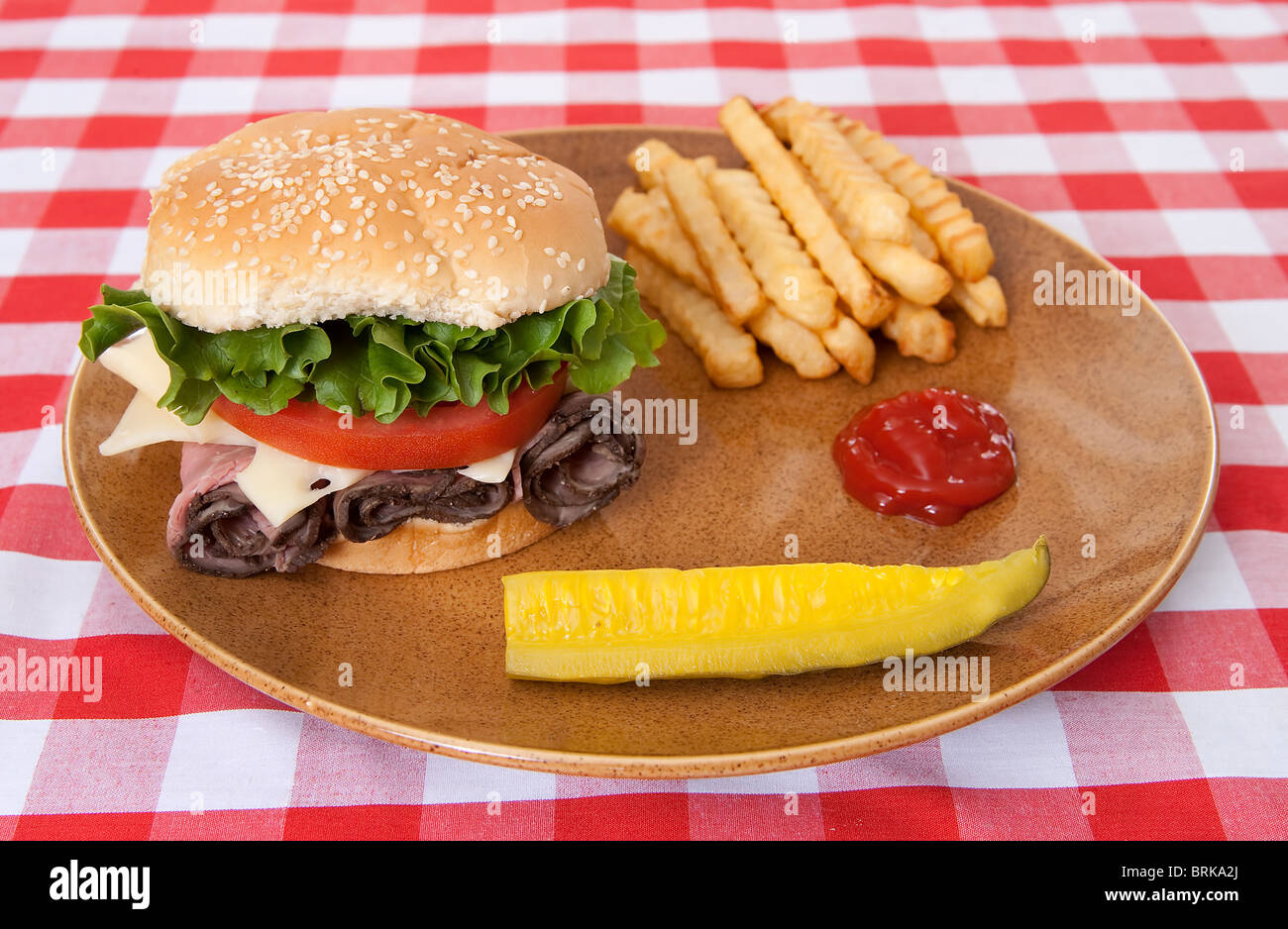 eine große Roastbeef-Sandwich mit Pommes Frites und einem Pickle Speer auf traditionelle rot-weiß karierte Tischdecke Stockfoto