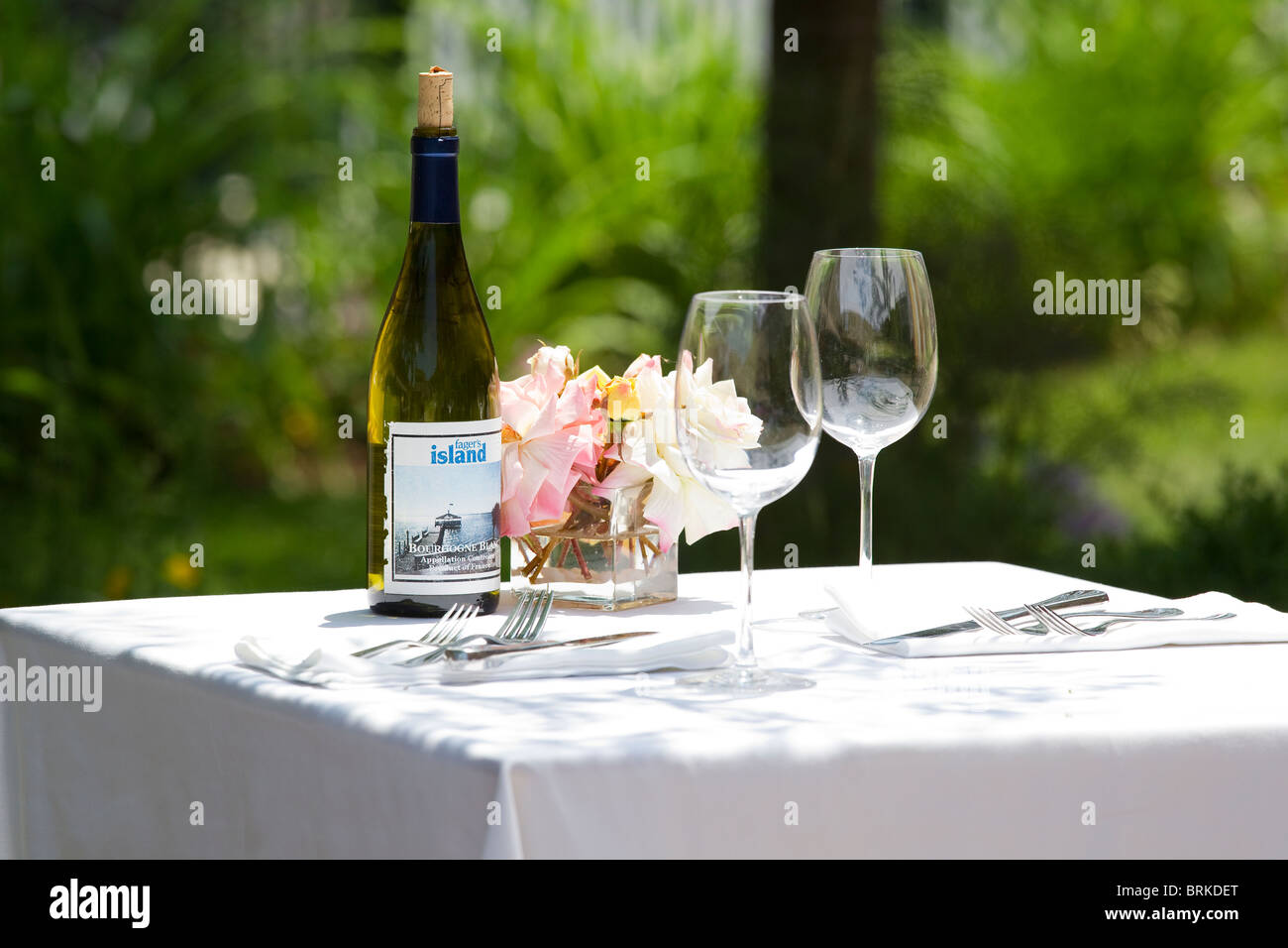 Weingläser und Weinflasche auf Tisch mit weißen Tischdecken außerhalb Stockfoto