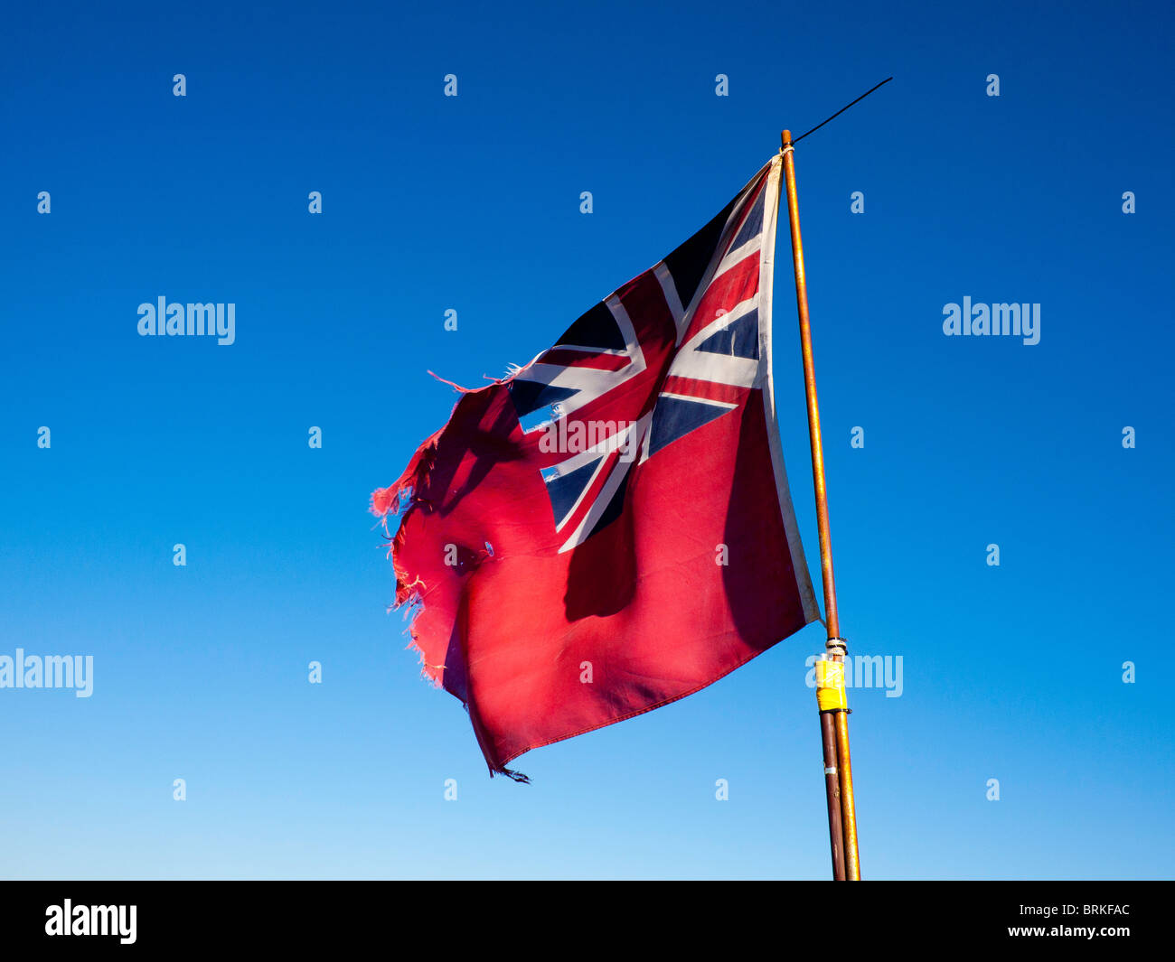 Alte abgenutzte RED ENSIGN Fahne gegen blauen Himmel Stockfoto