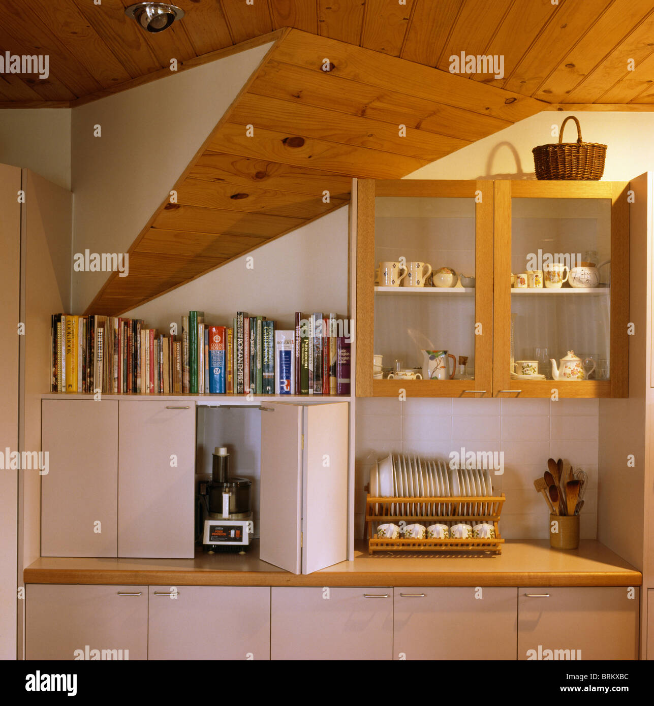 Koch-Bücher im Regal über dem Schrank verbergen elektrische Küchenmaschine  hinter Falttür in Einbauküche Einheit Stockfotografie - Alamy