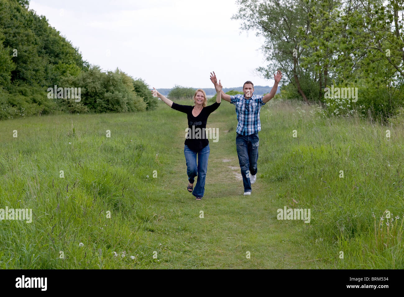 Verlassen glückliches Paar in Richtung der Kamera mit den Händen hoch Stockfoto