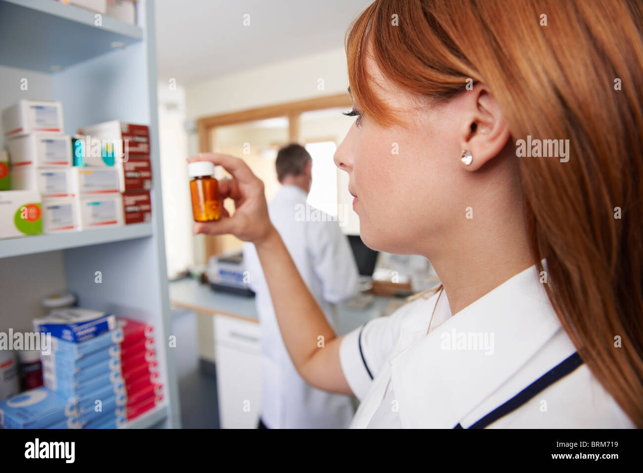 Apotheker, die Pillen in der Flasche zu betrachten Stockfoto