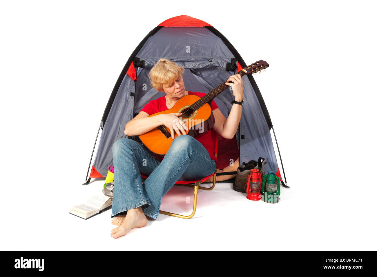 ältere Frau mit Gitarre auf dem Campingplatz Stockfoto