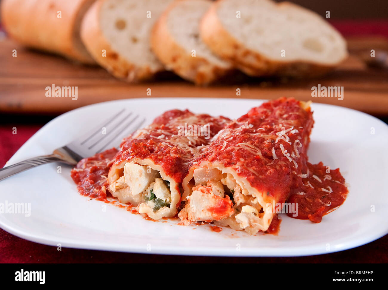 zwei leckere gefüllte Manicotti Muscheln gekrönt mit Pasta-Sauce und italienisches Brot auf der Seite Stockfoto