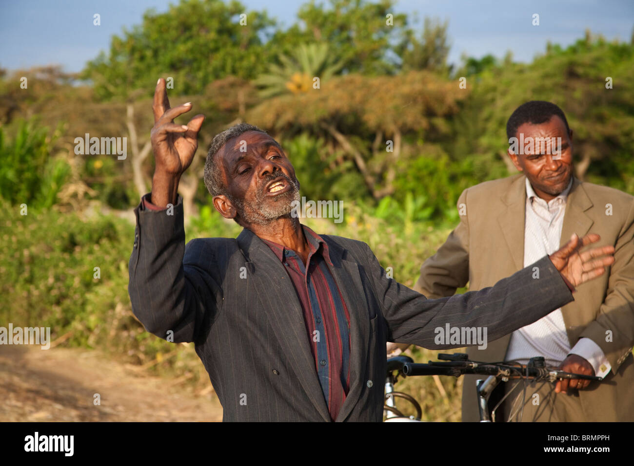 Ein freundlicher älterer Mann liefert theatralisch seinen Punkt während eines Gesprächs am Ufer des Sees Awassa am Abend Stockfoto