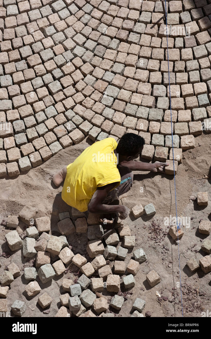Draufsicht eines Arbeitnehmers Verlegung ein Kopfsteinpflaster Steinpflaster in eine Technik gelernt während der Kolonialzeit von italienischen Handwerkern Stockfoto