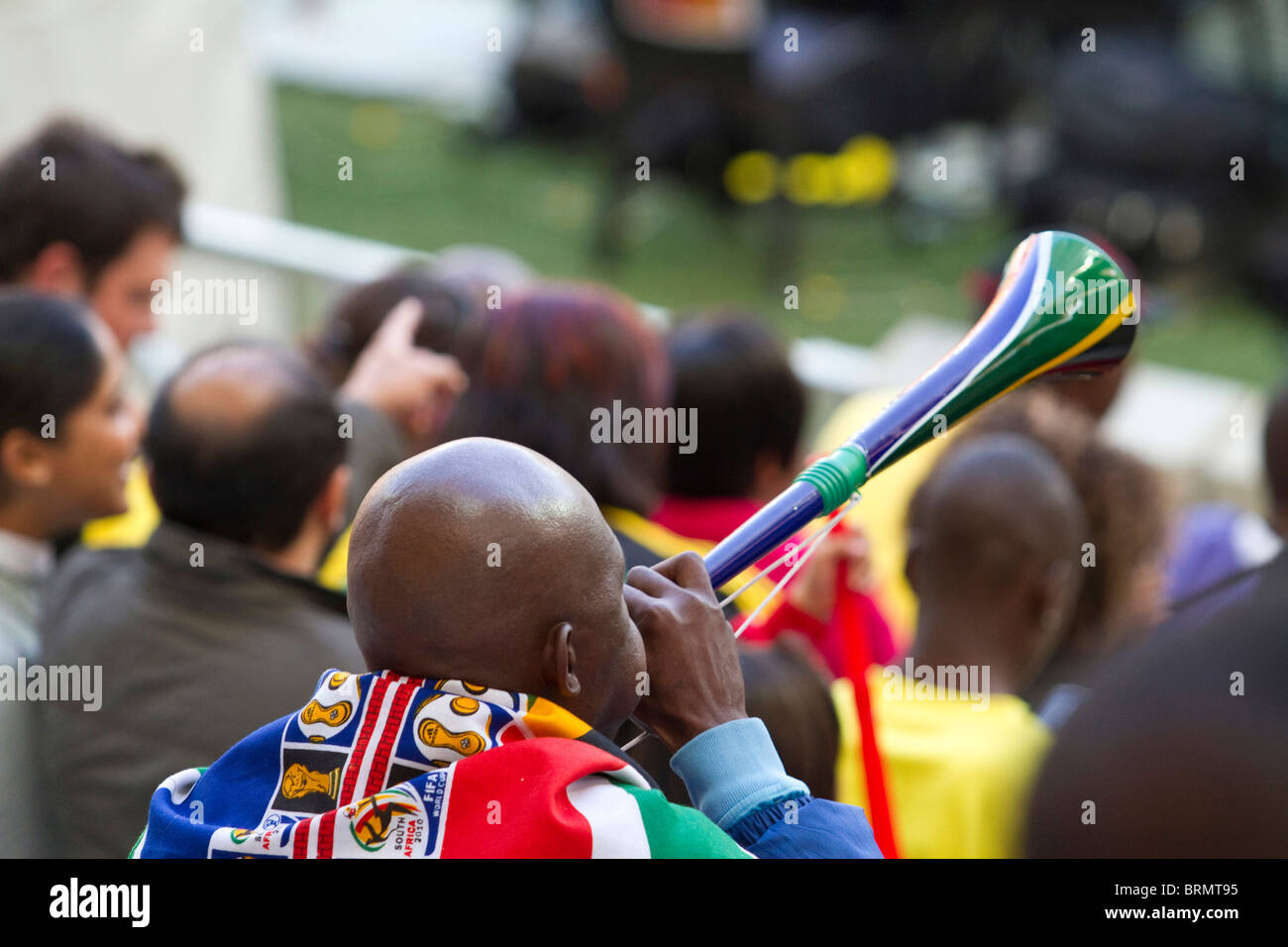 Rückansicht des ein Fußball-Fan drapiert in einem South African World Cup Fahne weht eine Vuvuzela während der WM 2010 Stockfoto