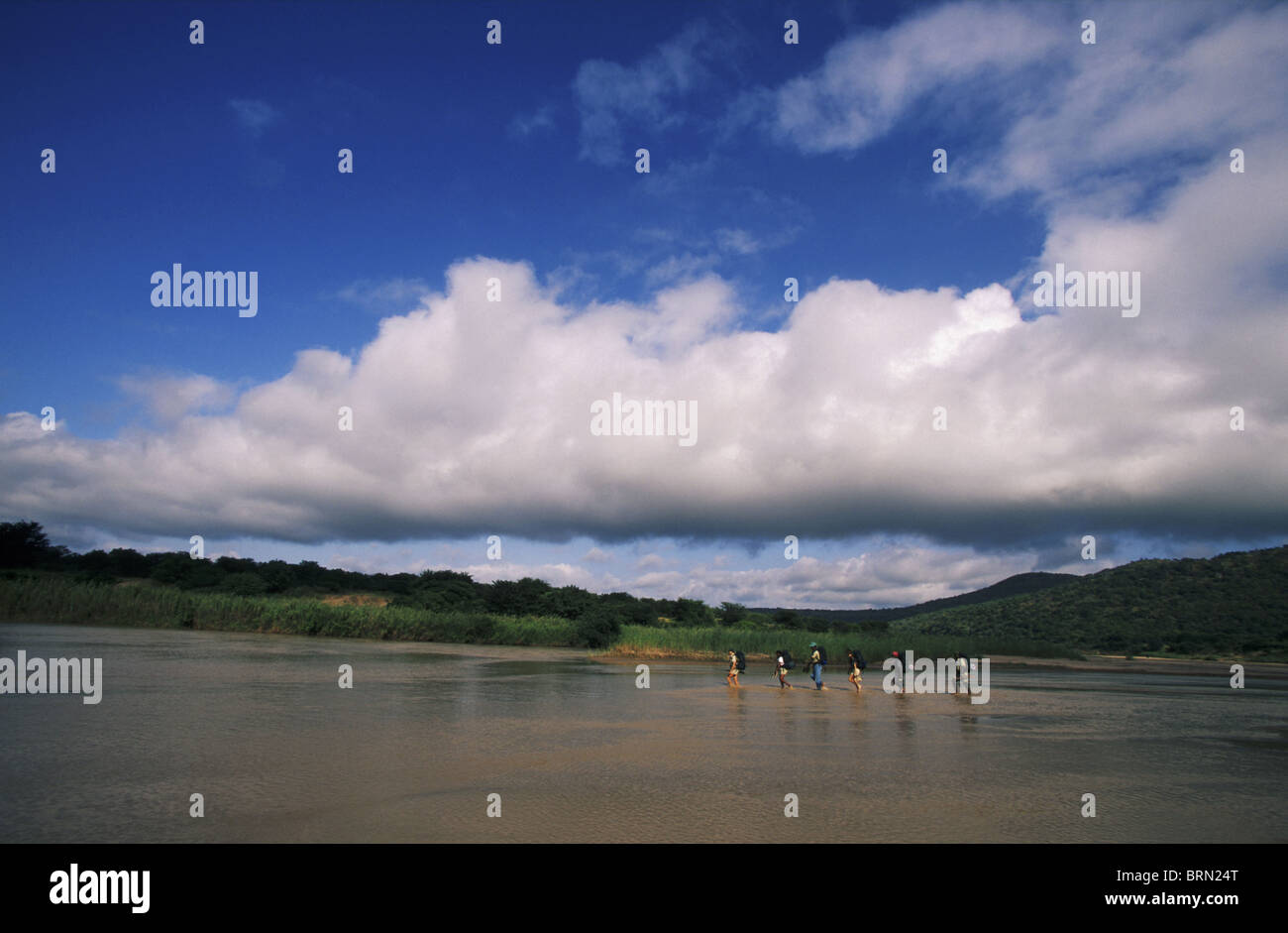 Wanderer und bewaffnete Wachen Spiel durchwaten White Umfolozi River auf einer geführten Wanderung durch den Umfolozi Game Reserve Stockfoto