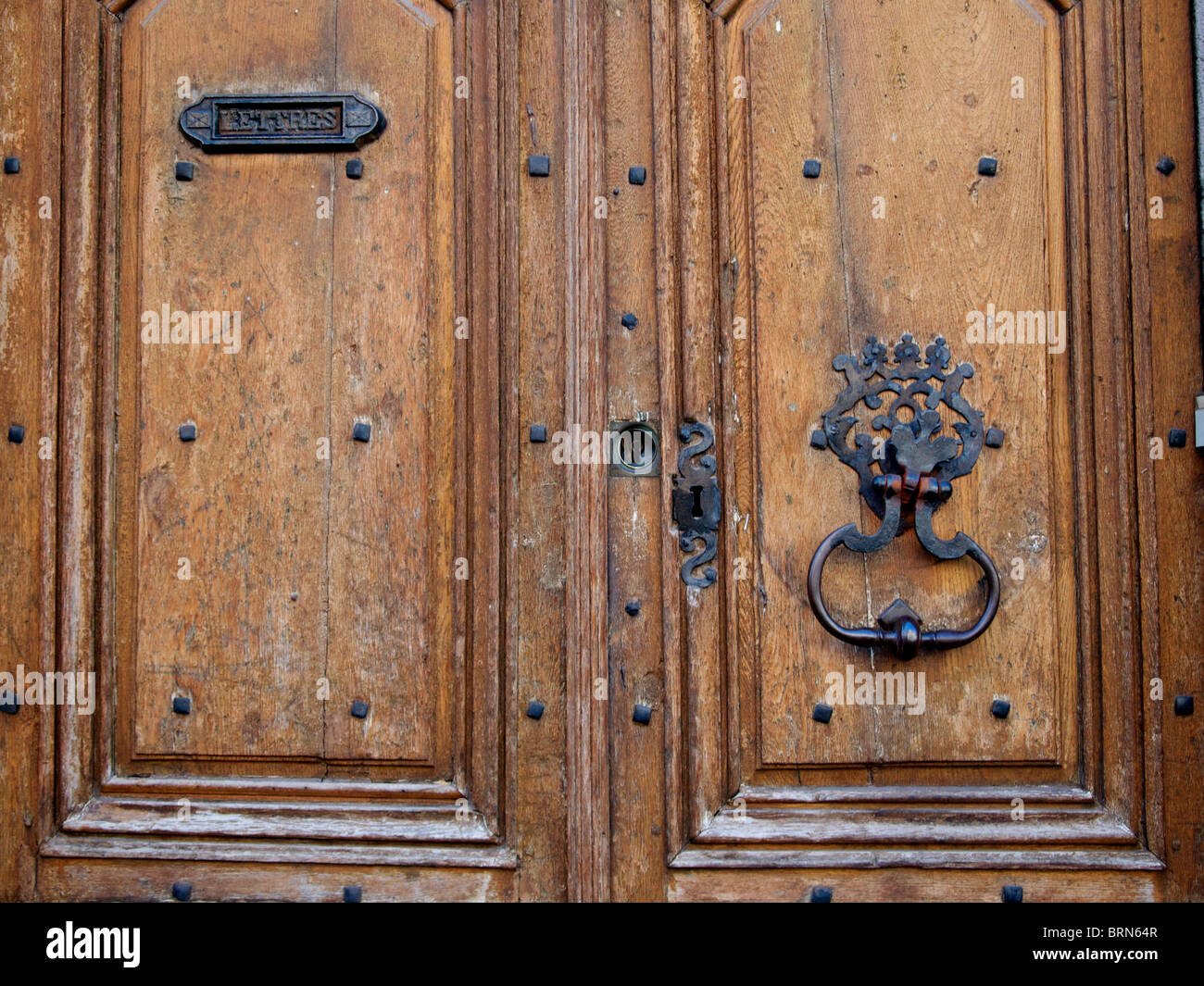 Detaillierte Holztür mit komplizierten Designs und schwerem Metallklopfer in einer rustikalen Umgebung Stockfoto