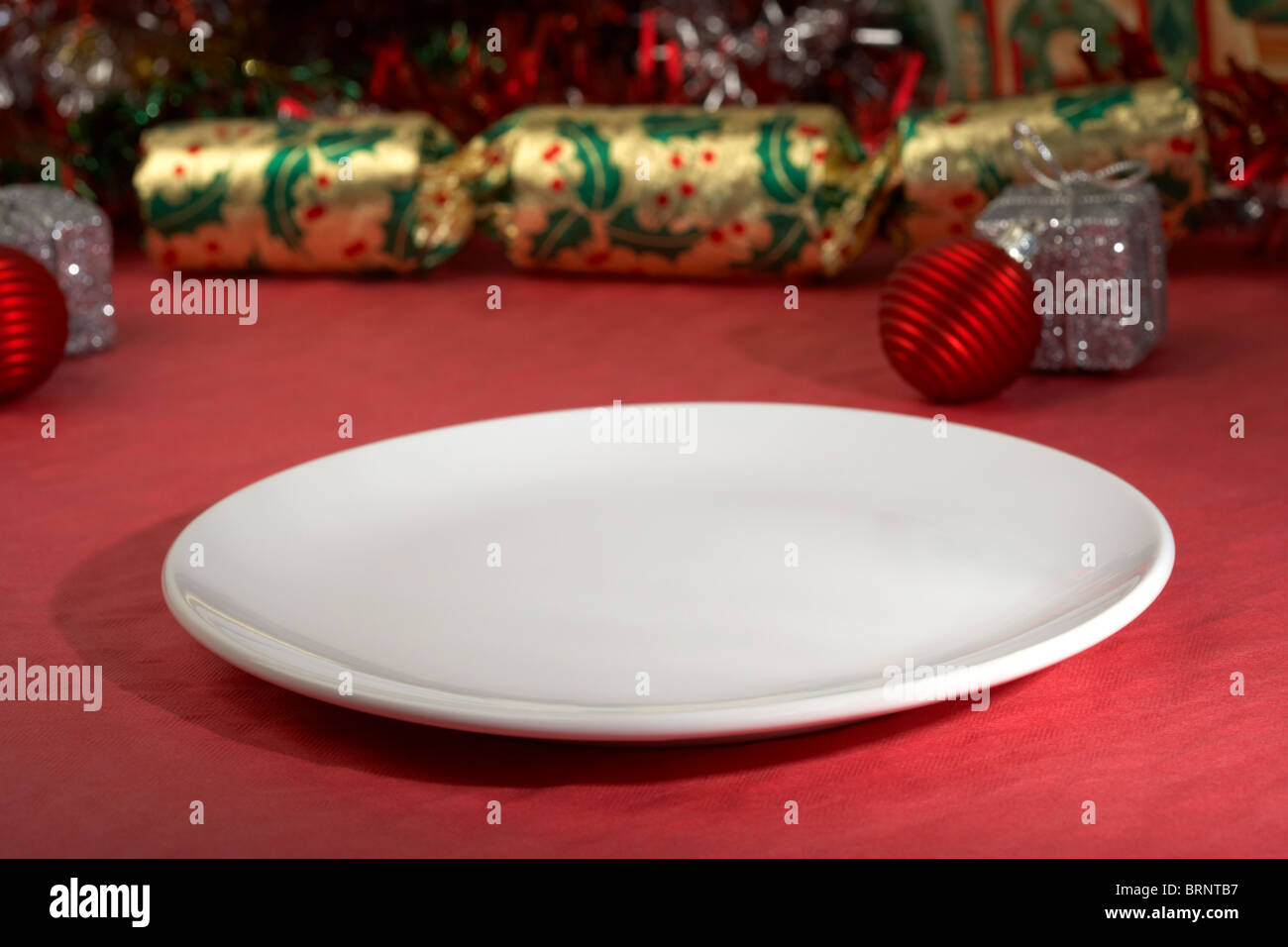 kleine weiße leere Dessertteller sitzt neben Weihnachtsdekorationen Stockfoto