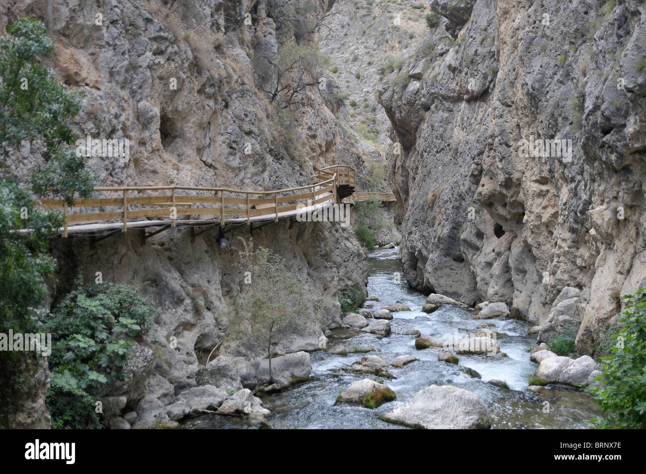 Hölzerne Flussbrücke Gehweg entlang Fluss-Schlucht und Brücke Stromschnellen Schienen Felsen Stockfoto