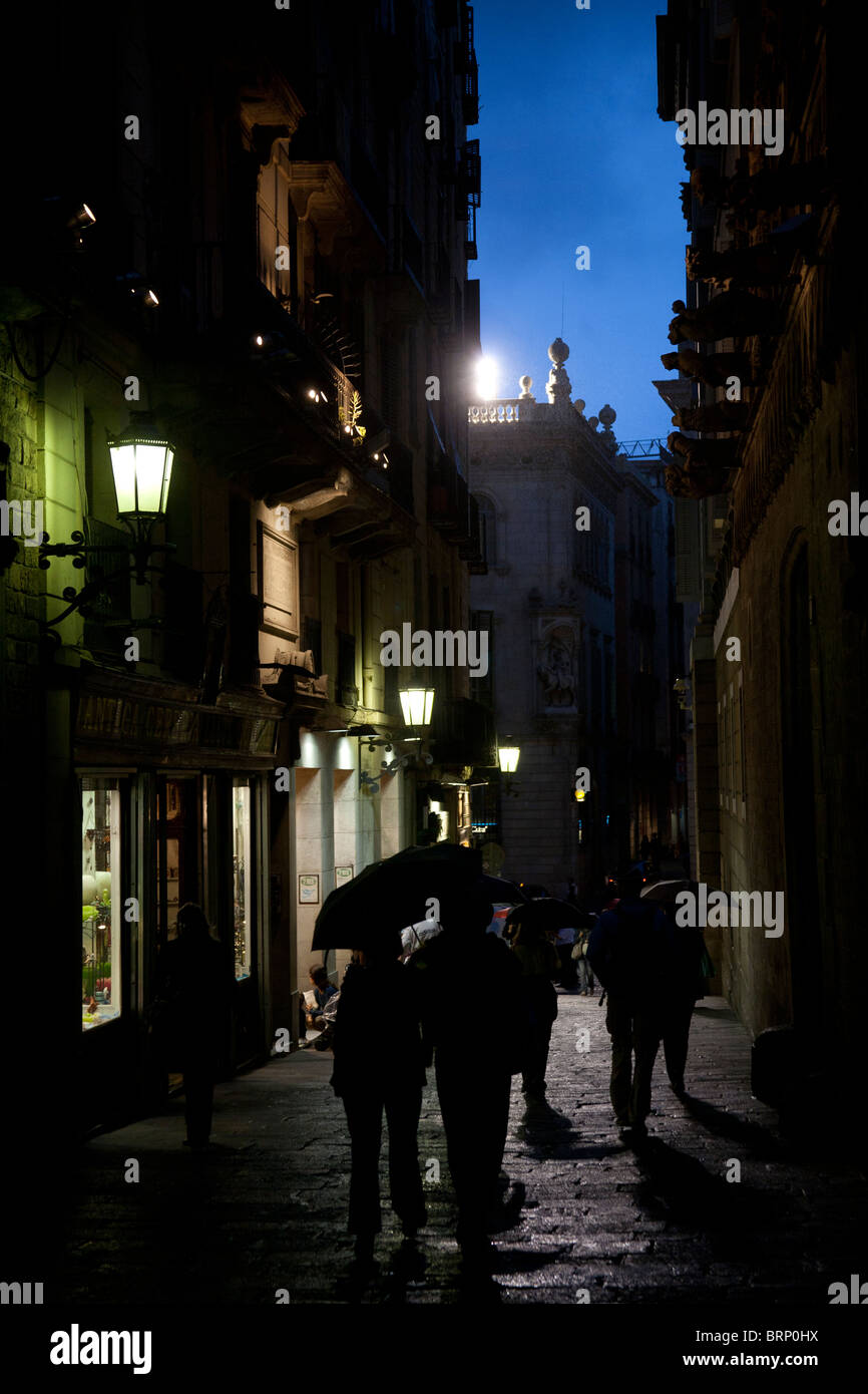 Menschen wandern in den Regen in einer dunklen Straße in der Nacht in das gotische Viertel oder Barrio Gotico-Barcelona, Spanien Stockfoto