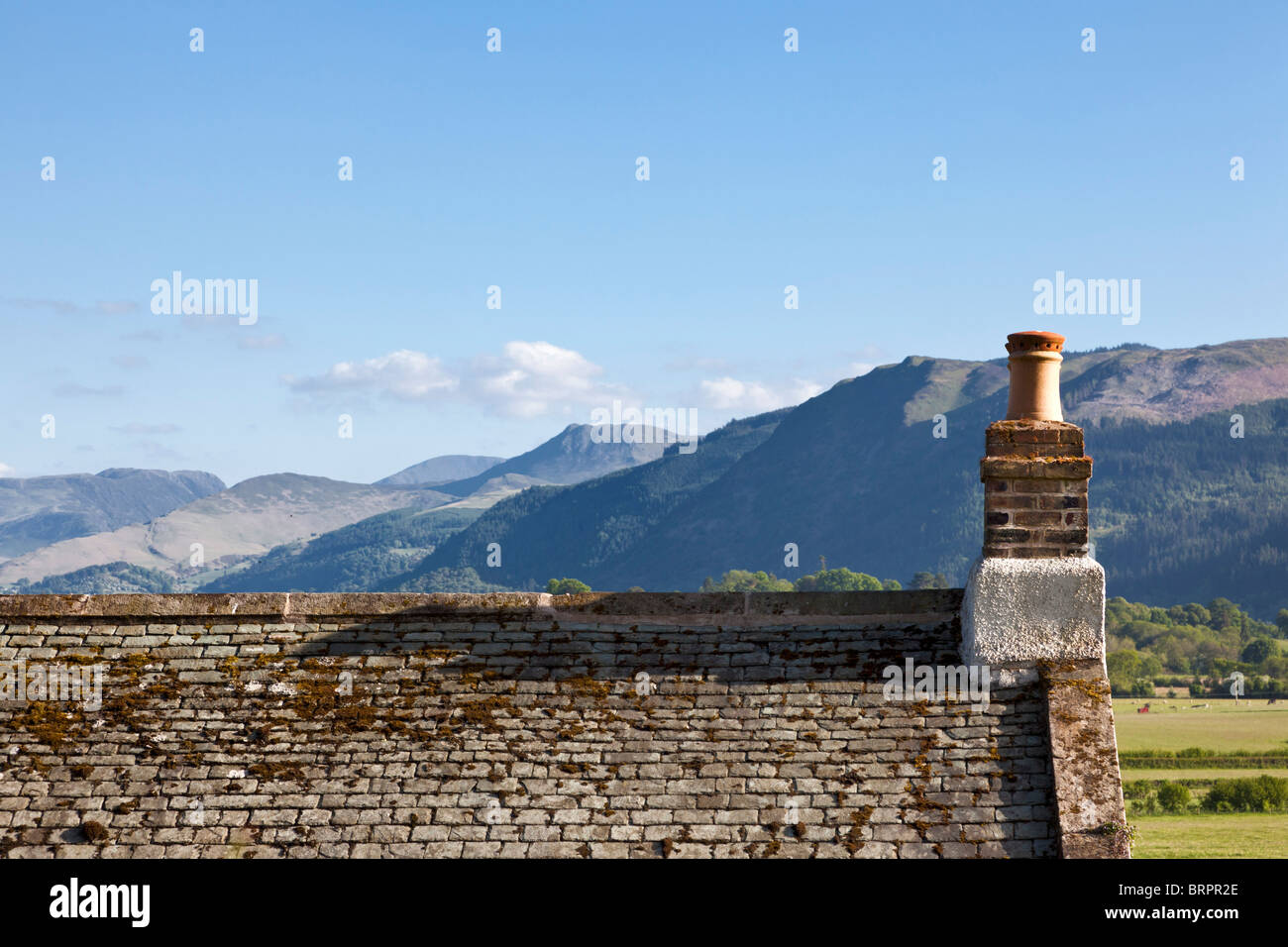 Altes Schieferdach Dach und Schornsteintopf mit Blick auf die Berge, Cumbria, England, Großbritannien Stockfoto