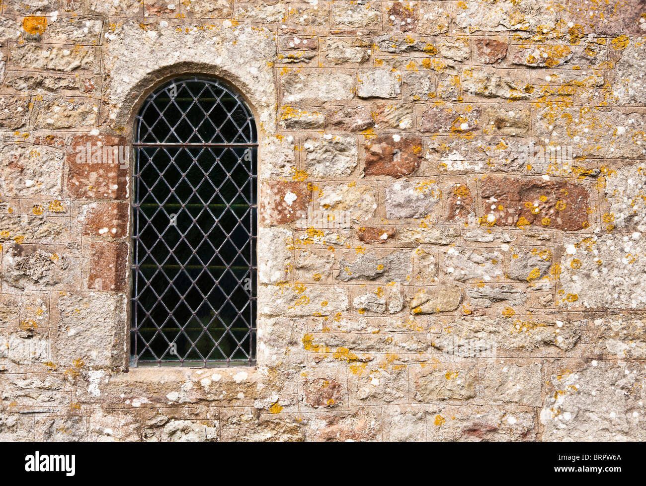 Nahaufnahme eines traditionellen gewölbten verbleites Kirchenfenster in Steinwand England UK Stockfoto