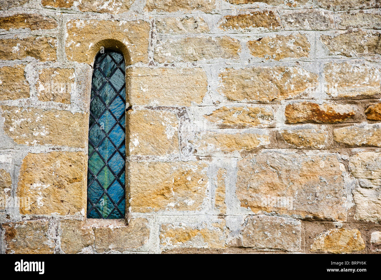Nahaufnahme eines traditionellen alten gewölbten verbleites Kirche Fensters in Steinmauer England UK Stockfoto