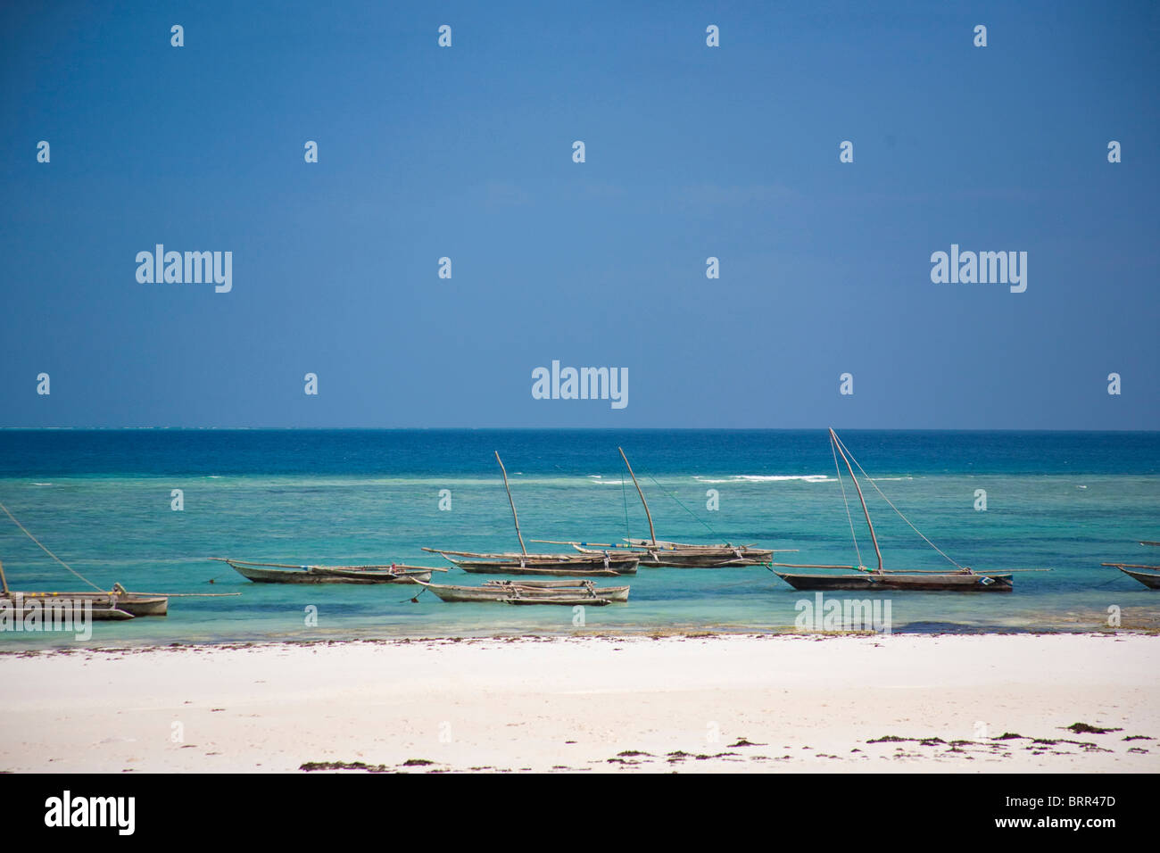 Strand-Szene mit Ausleger Angelboote/Fischerboote vertäut im seichten Wasser vor Mnemba Island Stockfoto
