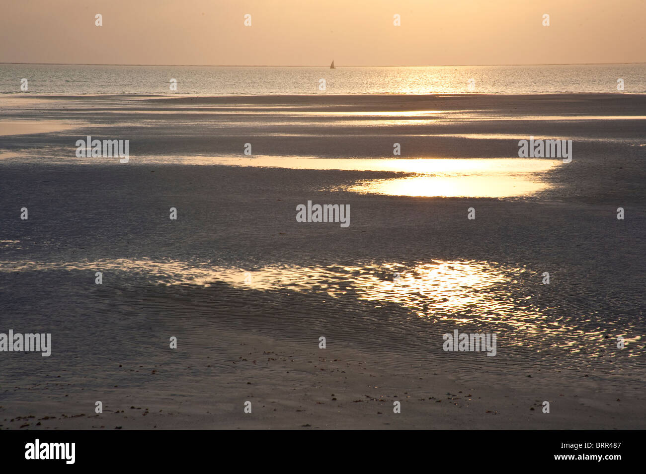 Einsame Insel Strand bei Sonnenuntergang mit entfernten Dhows am Meer Stockfoto