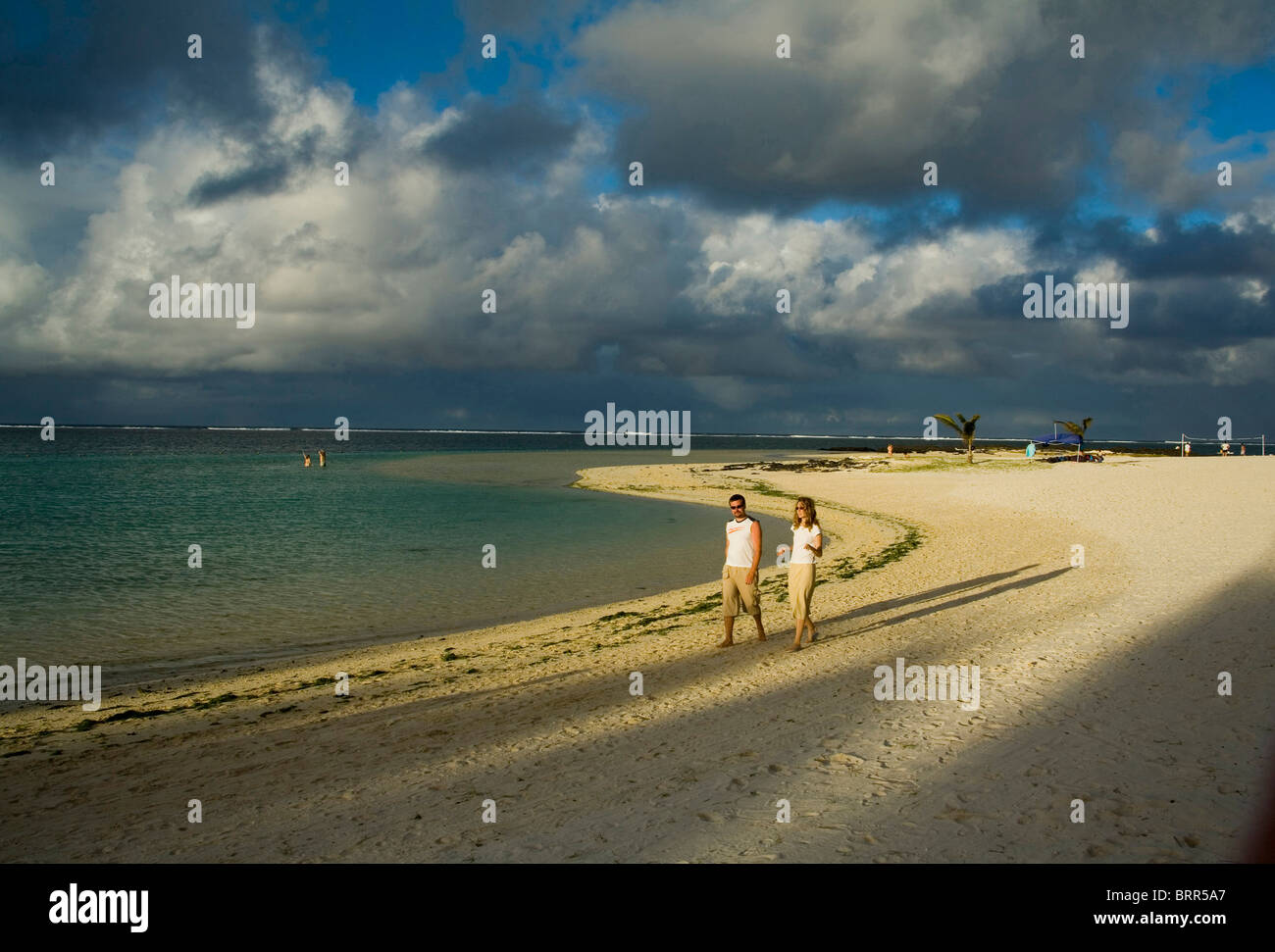 Menschen zu Fuß am Strand von Beau Rivage mit Gewitterwolken über sammeln Stockfoto