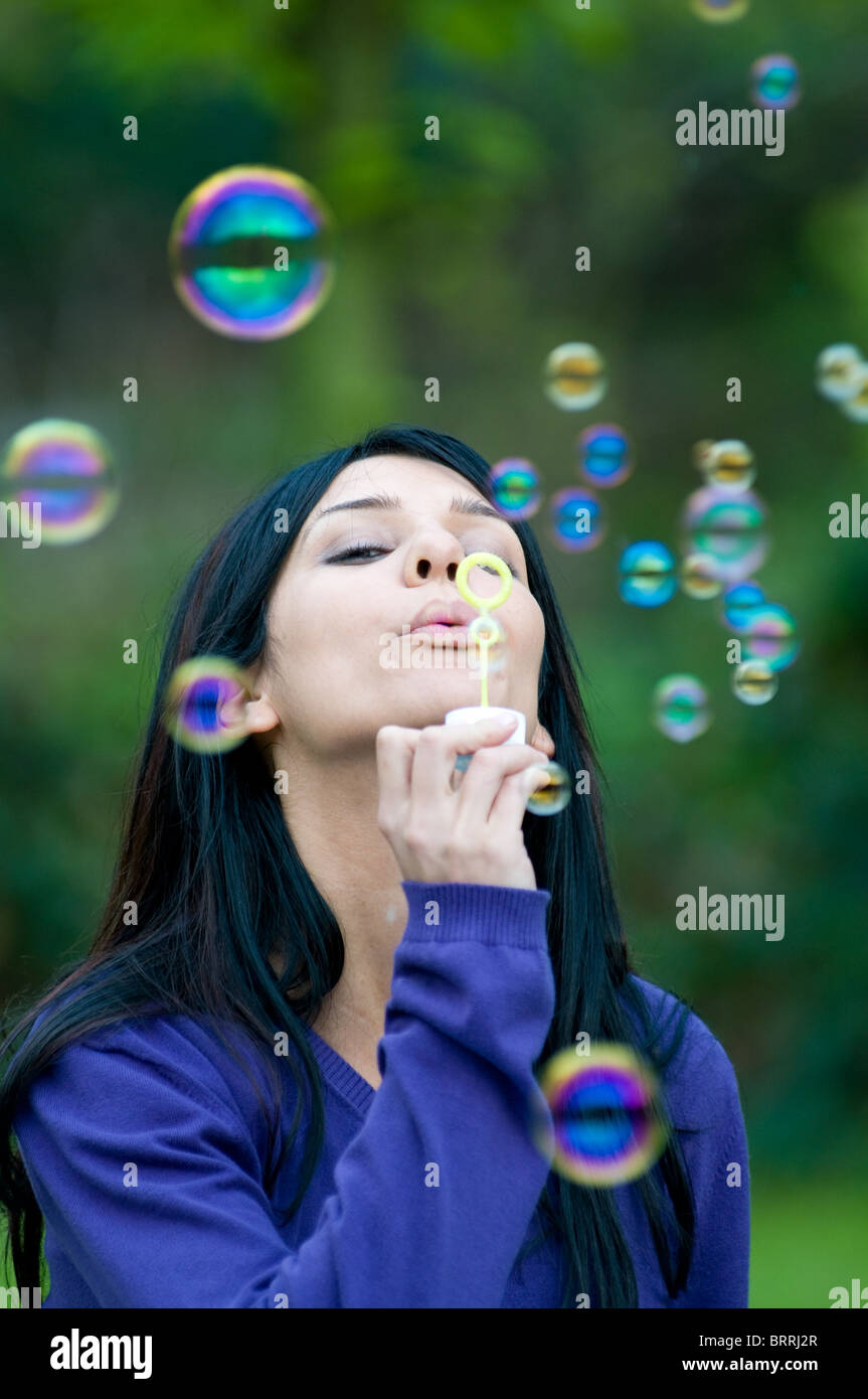 Junge schöne Frau bläst Seifenblasen im grünen Stockfoto