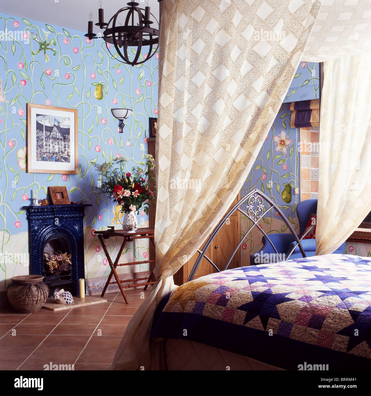Gemusterte cremefarbene Vorhänge auf Gothic-Stil Bett mit Patchwork quilt  im Schlafzimmer mit blassen blauen Tapete und Steinbruch Fliesenboden  Stockfotografie - Alamy