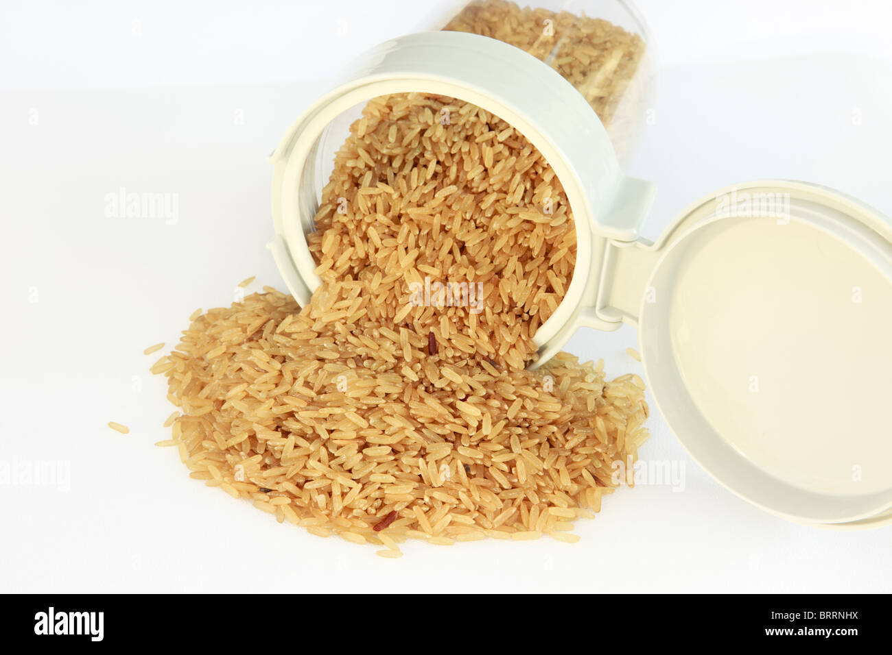 Stapel von ungekochten Reis verschütten aus einem Kunststoff essen Topf mit offenem Deckel oben Stockfoto