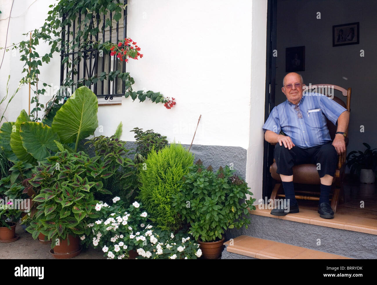 Älterer Herr saß in der Tür seines Hauses auf dem Festival von Mandel, Almogia Dorf, Provinz Malaga, Malaga, Spanien. Stockfoto