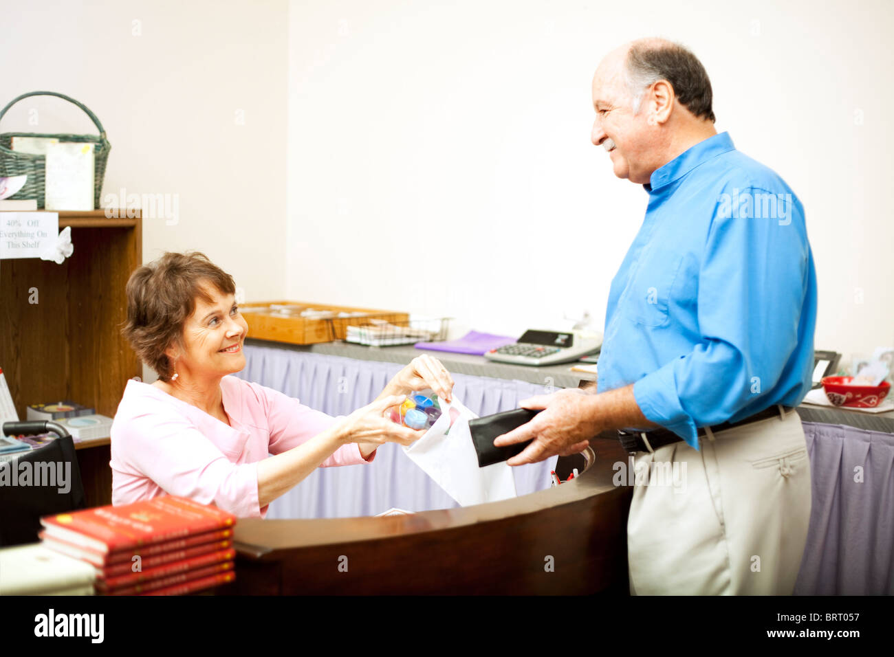 Verkäuferin in einem Rollstuhl-Beutel ein Kunde Kauf. Platz für Text. Stockfoto