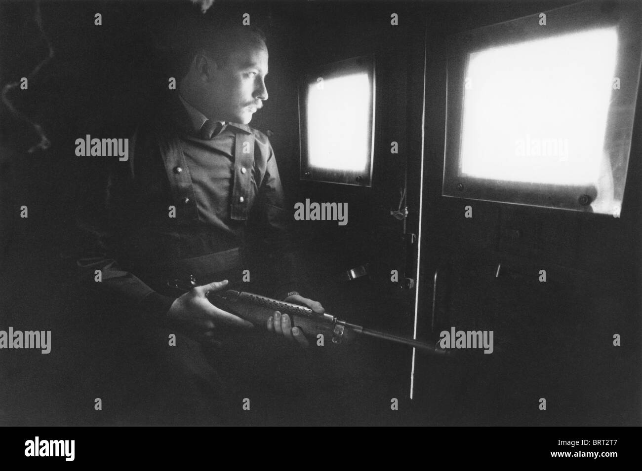 Ein bewaffneter Royal Ulster Constabulary-Offizier auf der Rückseite einen gepanzerten Landrover in Belfast Stockfoto