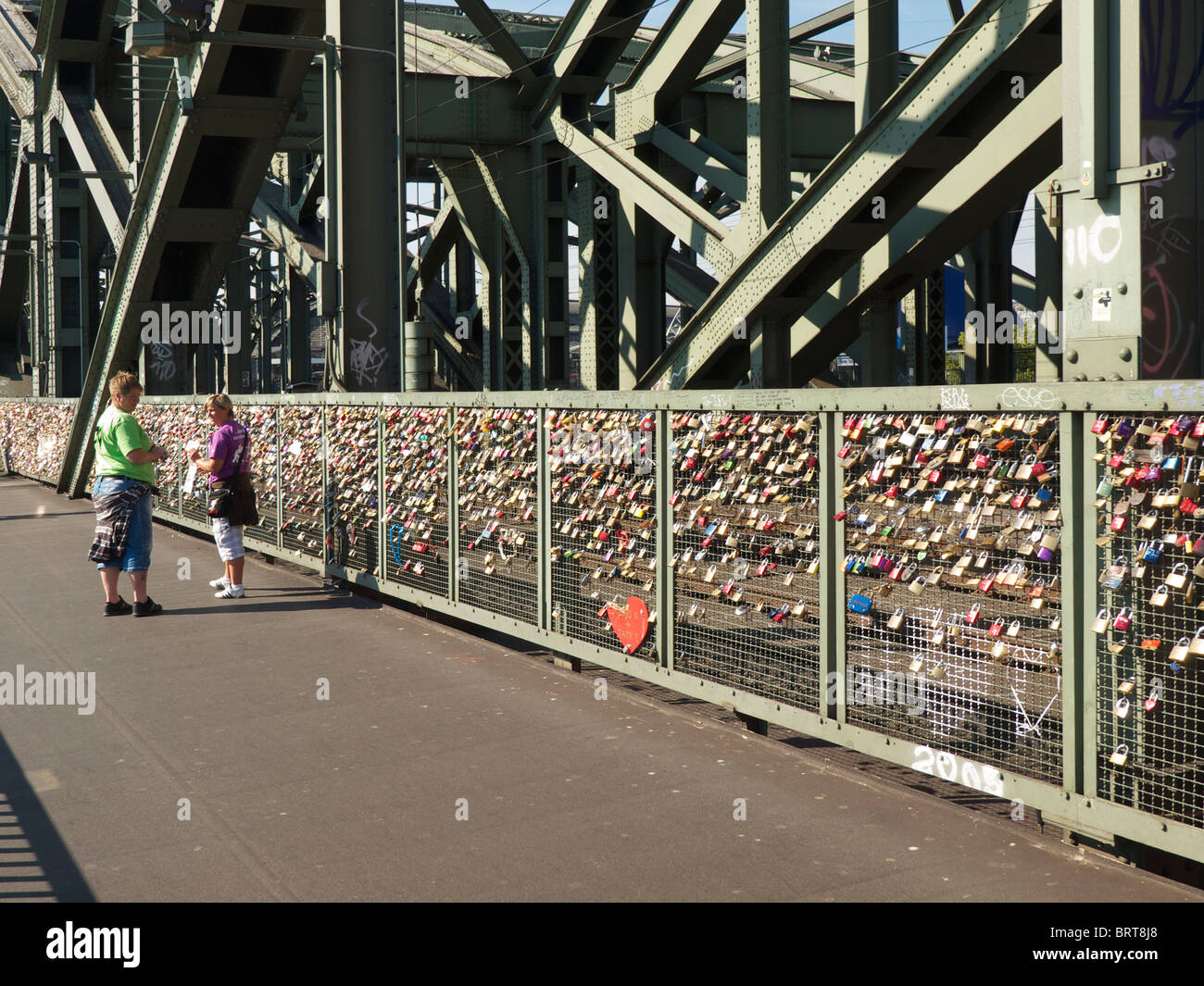 Viele Schlösser angebracht zur Hohenzollernbrucke Eisenbahnbrücke in Köln, mit paar vorbeigehen Stockfoto